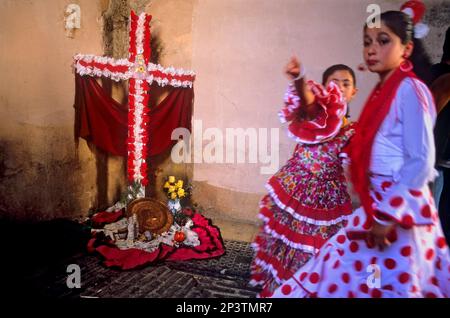 Dia de la Cruz, floral cross and girls in traditional dress `Un Chavico pa la Cruz´, at Arco de las Pesas,Albaicin quarter, Granada, Andalucia, Spain Stock Photo